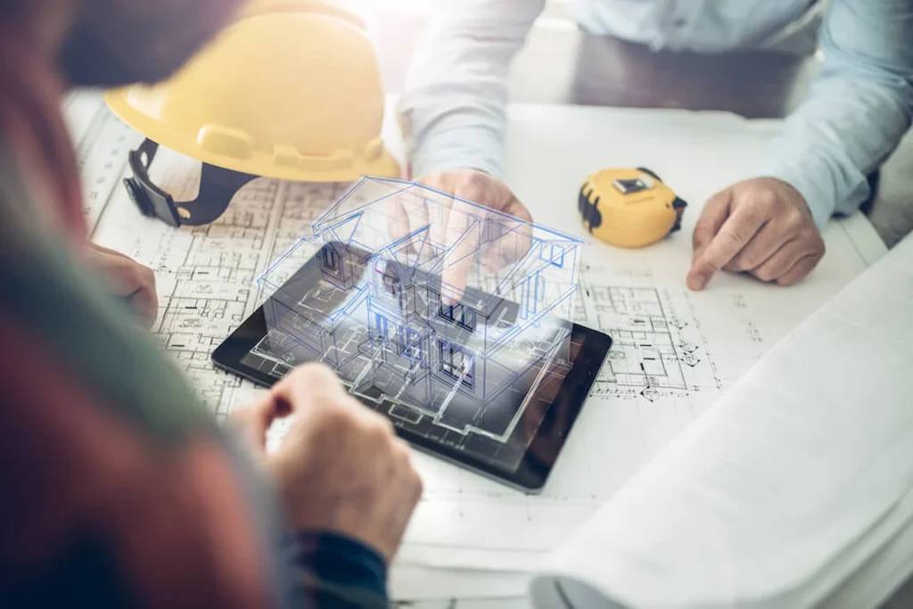 Architects and engineers reviewing digital house plans and 3D architectural design on a tablet with construction blueprints.
