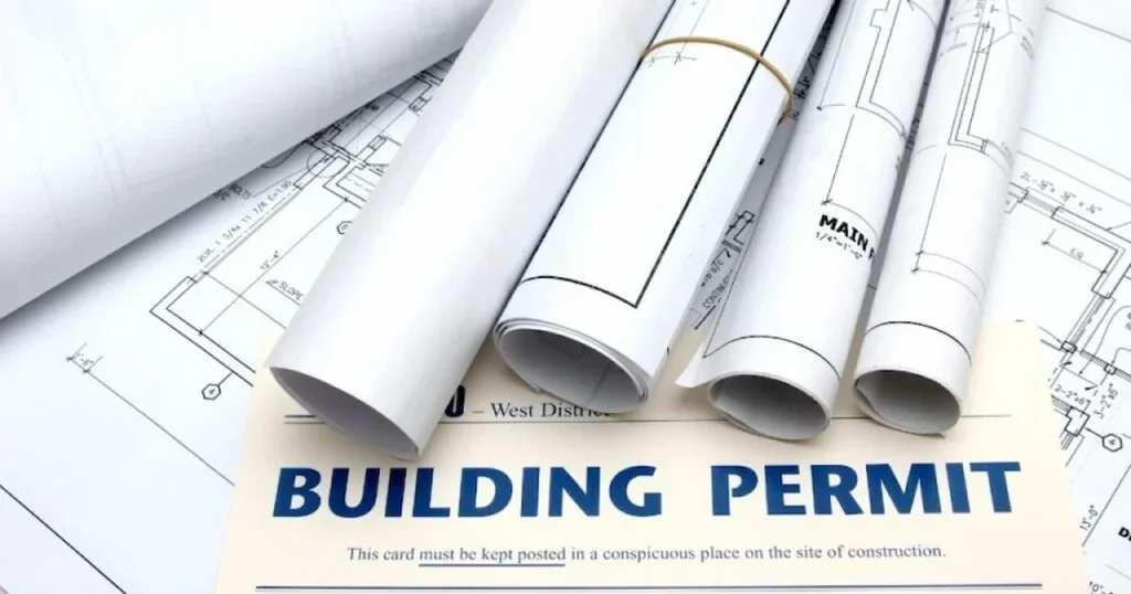 Blueprints and rolls of architectural drawings sitting on top of a building permit document, which is required alongside a Florida deck permit site plan.